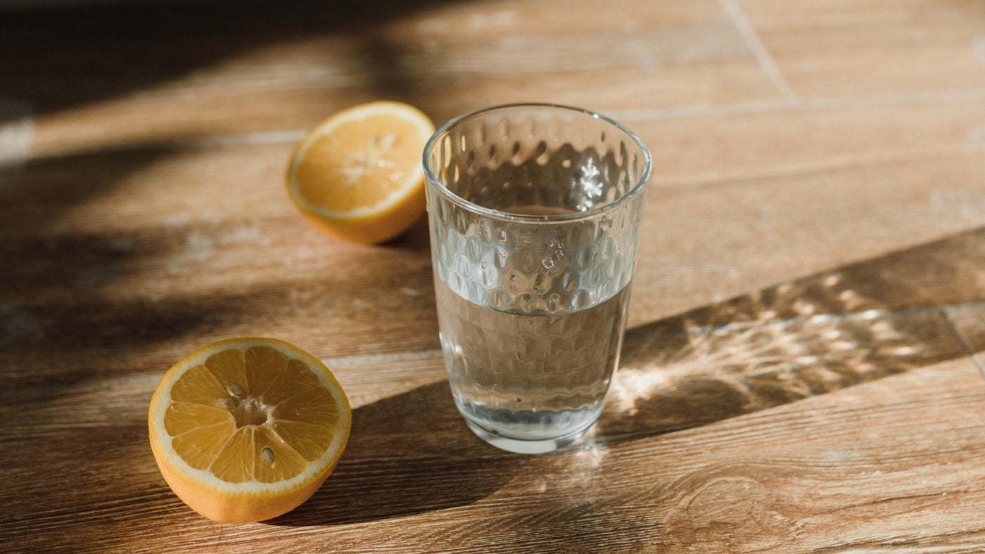 A glass of water next to two lemon halves