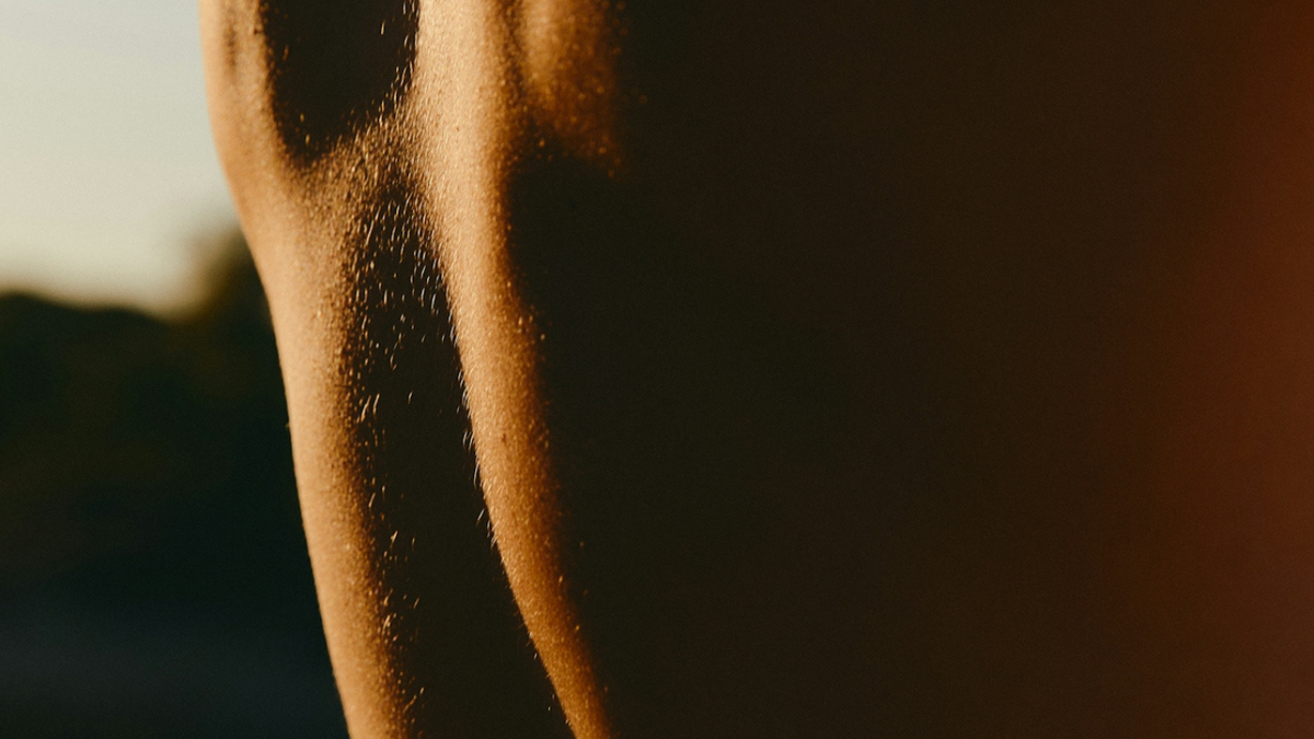 Close-up of sunlit human skin with fine body hair.